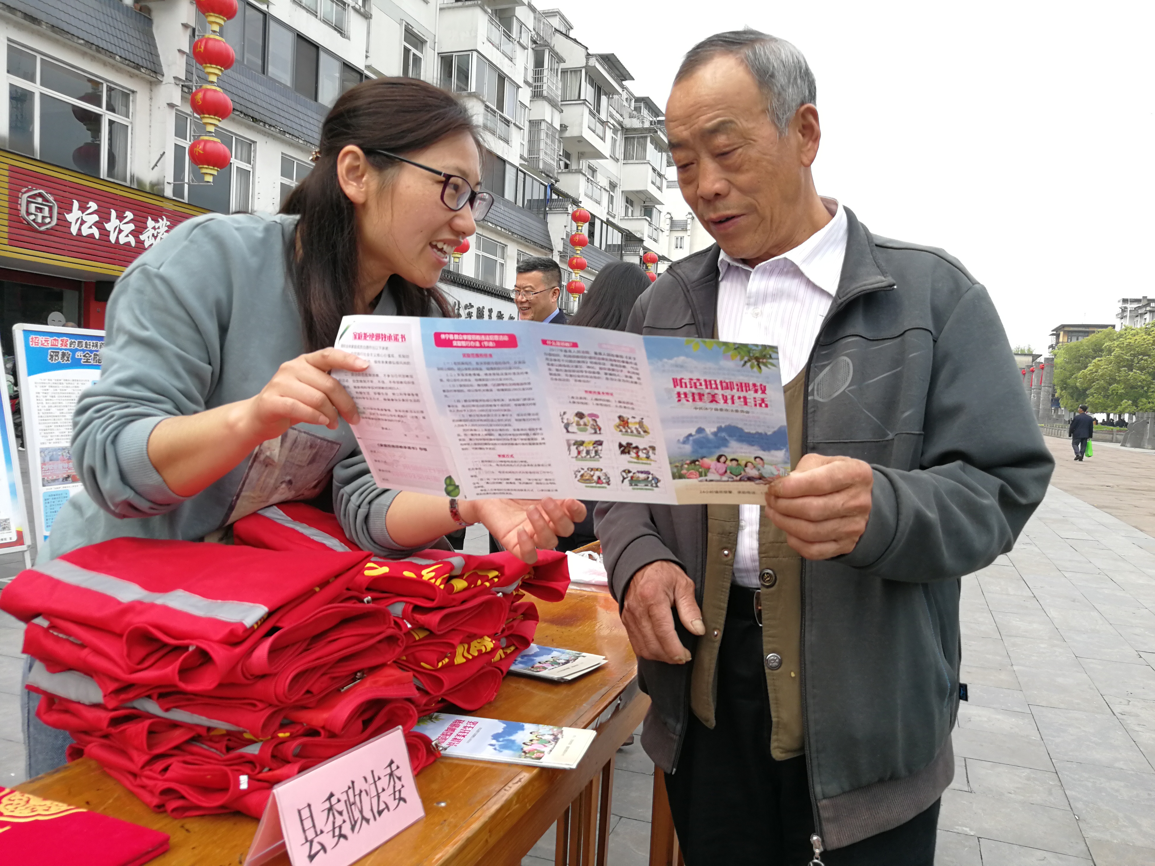 休宁县政法委工作人员向群众发放反邪教宣传册，介绍反邪教基本常识