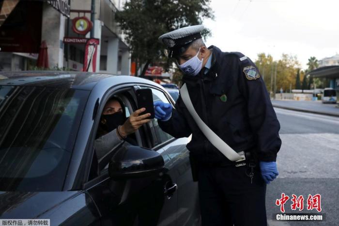 资料图:希腊雅典,一名警察正在检查司机证件,确定其出行目的。 点击进入下一页