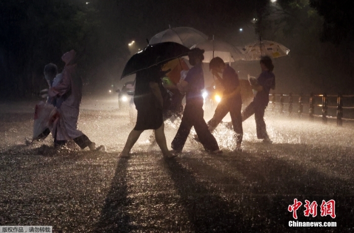 当地时间2022年8月8日，韩国首尔遭遇特大暴雨。截至8日21时，首尔部分地区降雨量在1个小时内达到141.5毫米，超过了有相关记录以来首尔每小时降雨量的历史最高值。首尔多个地段被水淹没，多条地铁线路区间运行或停运，还接连发生地面沉降、停电等事故。韩国行政安全部当天21时30分将灾害危机警报从“注意级”上调至“警戒级”。图为首尔江北地区，人们在暴雨中涉水出行。