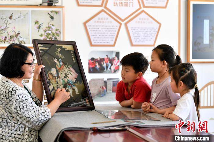 图为裴小苓正在向孩子们介绍玻璃油画历史及工艺技巧。　高丹钰 摄