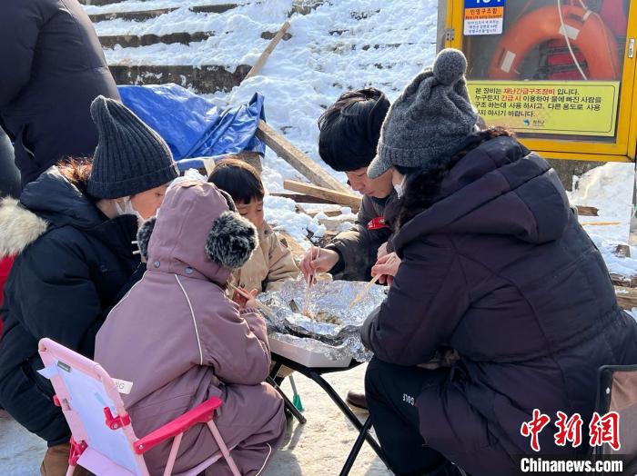 图为游客现场享用烤鱼。 刘旭 摄 图为游客现场享用烤鱼。 刘旭 摄