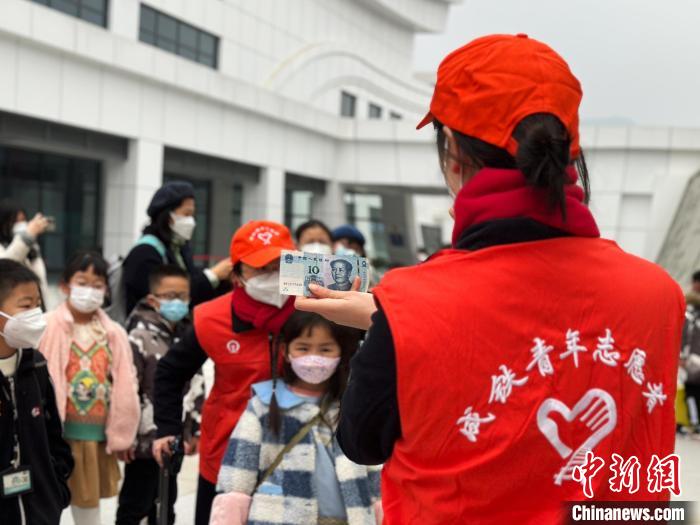 图为志愿者正在向诗词少年们展示第五套10元人民币，其风景图案就位于奉节夔门。　中国铁路成都局集团有限公司供图