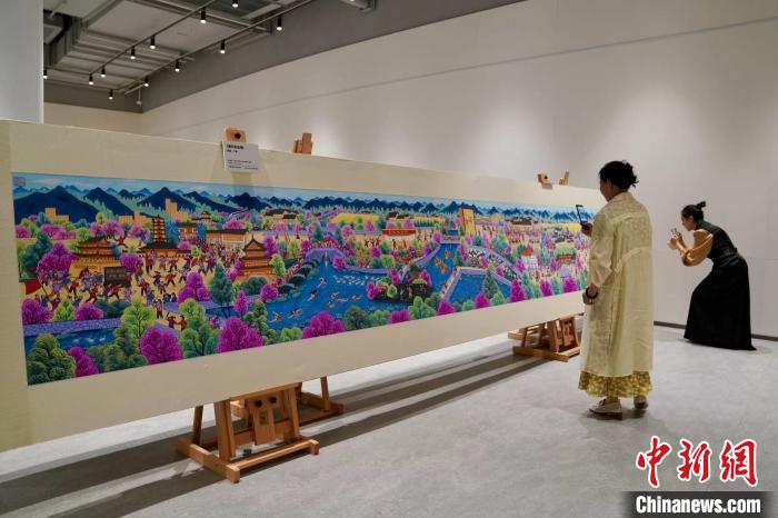 两位画家观赏、拍摄参展作品。 钱晨菲 摄 两位画家观赏、拍摄参展作品。 钱晨菲 摄