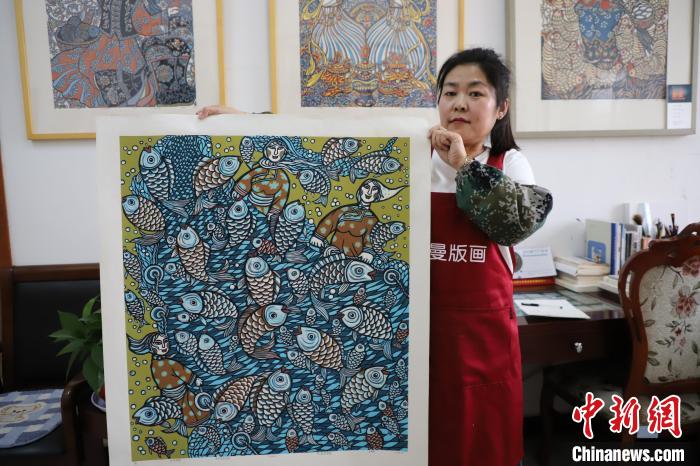 图为王秀春展示版画作品。　张林虎 摄